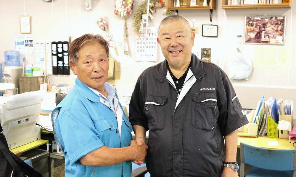 北山魚伊 濱中社長と浅見水産 浅見社長が笑顔で握手を交わす様子